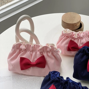 Detail of waffle texture makeup bags featuring large red bows and ruffled edges on a table