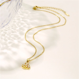 Golden stainless steel heart pendant necklace with zircon crystals on a chic beige background