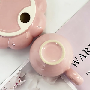 Top-down macro view of pink polished ceramic sunflower tea set and small matching cup