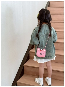 Girl wearing a pink cartoon bear crossbody bag with strawberry decor on a bright staircase