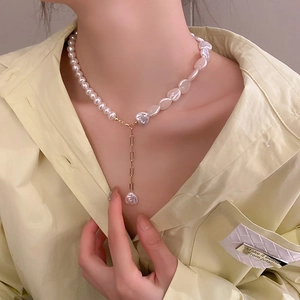 Detail view of irregular pearl heart necklace on model with golden chain accents
