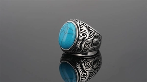 Macro detail of men's vintage steel ring featuring blue stone and engraved floral patterns