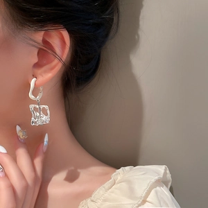 Irregular acrylic ice cube hoop earrings with silver pins worn by a model in a side view