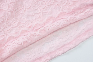 Close-up of pink lace fabric with intricate floral embroidery and sheer mesh texture