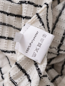 Détail de l'étiquette en tricot texturé montrant 100 pour cent polyester et taille S