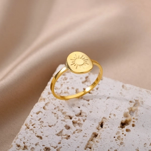Detailed view of an 18K gold stainless steel ring with a sun motif on a beige stone