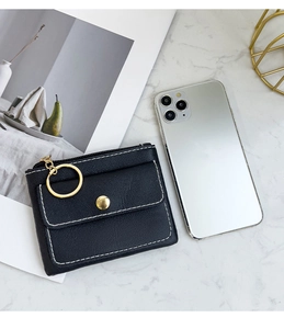 Chic black faux leather coin purse with white stitching on white marble background