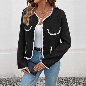 Detail of waffle texture knit cardigan featuring white wavy embroidery and open front design