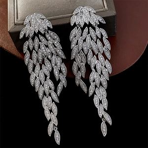 Macro detail of silver leaf tassel earrings with white zircon stones on leather background