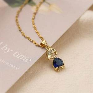 Macro detail of gold-plated necklace with a heart-shaped blue zircon and micro-pave stones