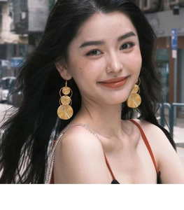 Detailed close-up of layered golden geometric spiral disc earrings worn by a model