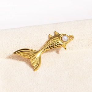 Macro shot of a golden fish-shaped pendant featuring a white pearl and scale texture