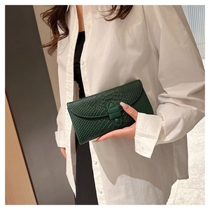 Detail of dark green embossed crocodile leather wallet held by hand for a vintage look