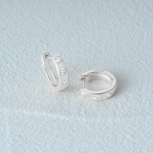 Close-up of S925 sterling silver hoop earrings with triple inlaid cubic zirconia stones