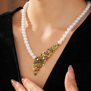 Détail du collier vintage avec perles blanches et pendentif doré aux pierres précieuses