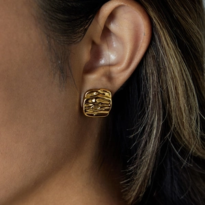Luxurious hammered gold square earrings in stainless steel on model's ear with high shine