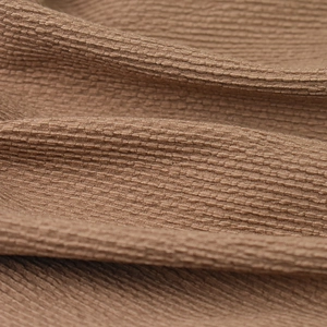 Macro texture of soft coffee-colored knitted fabric with waffle pattern for beanies