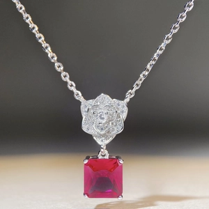 Macro shot of silver camellia pendant with red ruby gemstone and delicate floral petal details