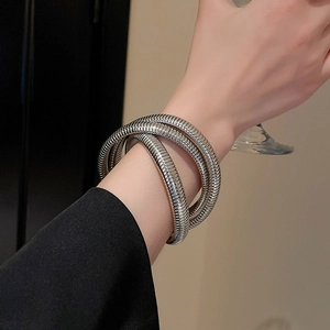 Detailed view of women wearing silver spiral multi-layer metal bangle with sleek finish