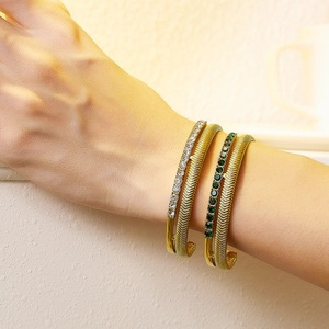 Close-up of gold double-layer spiral bracelets with pearl and emerald zircon on model wrist