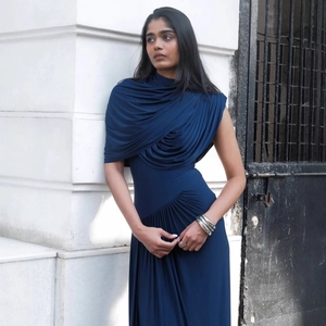 Detail of elegant navy blue evening gown featuring side ruching and draped fabric texture