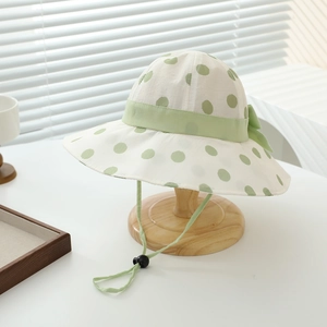 Detailed view of white polka dot bucket hat with green bow and adjustable windproof drawstring