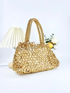 Nahaufnahme der goldenen Perlen-Handtasche mit gewebter Metallstruktur auf weißem Grund