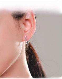 Detail of silver drop earrings with pavé zircons and smooth teardrop on a model ear