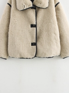 Detailed view of beige faux fur jacket featuring black contrast trim and plush lapel