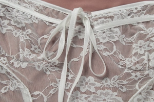 Detail van wit bloemenkant met satijnen lint en een zachte voering van stof
