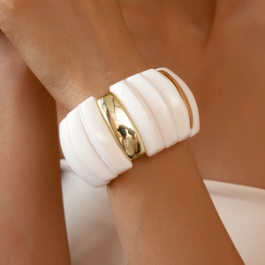 Macro shot of irregular acrylic and gold metal segments on a wide geometric bracelet