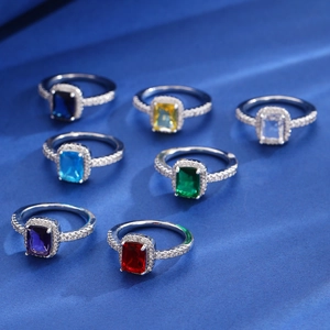 Detailed row of silver rings featuring vibrant rectangular gemstones on blue silk background
