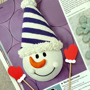 Detailed view of snowman head topper with purple hat and red glove cake inserts