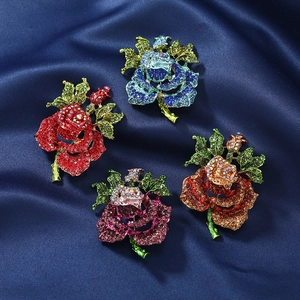 Detail view of four vintage rose flower brooches with colorful rhinestones on blue silk