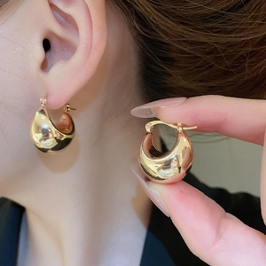 Detailed close-up of golden chunky hoop earrings with a polished metallic finish