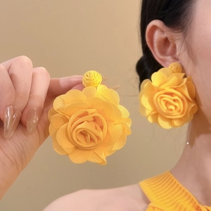 Detail of yellow fabric flower earrings on model highlighting the elegant floral design