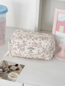 Détail d'une trousse à maquillage matelassée à fleurs avec poignée et fermeture éclair
