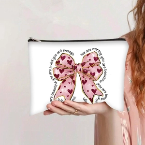 Close-up of canvas makeup bag with pink bow, red hearts and motivational phrases
