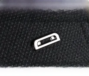 Macro shot of black waffle knit fabric with a silver metal brand logo for winter hats