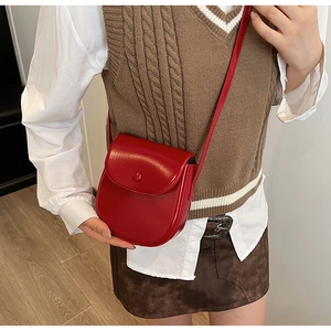 Detailansicht einer leuchtend roten Satteltasche kombiniert mit einer Retro-Strickweste