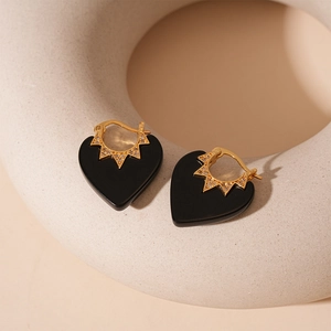 Détail des boucles d'oreilles cœur dorées avec émail noir et sertissage zircon