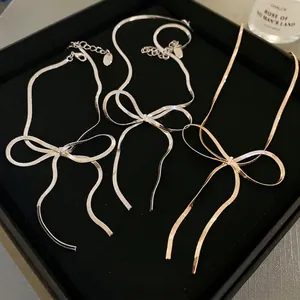 Minimalist bow-knot snake chain necklaces in gold and silver finish on black velvet