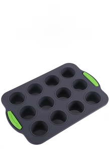 Detail of 12-cup silicone muffin tray with green handles and heat resistance info