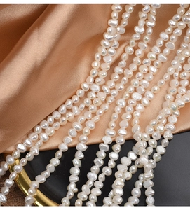 Macro shot of 4-5mm baroque freshwater pearls with natural luster on silk fabric