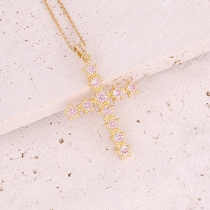Macro detail of 18K gold-plated cross pendant with sparkling micro-pave pink cubic zirconia