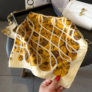 Gros plan d'un foulard en soie jaune avec motifs floraux rétro et coutures soignées