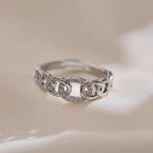 Macro detail of silver chain ring with pavé cubic zirconia on textured fabric