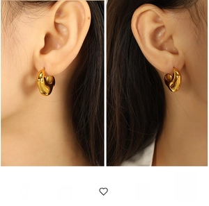 Detailed view of model wearing thick gold geometric earrings with a modern curved design