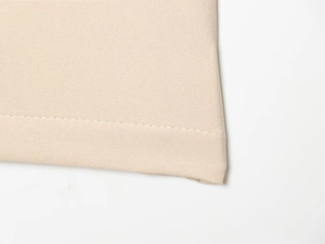 Gros plan sur la texture du tissu sergé beige et les coutures de ce short décontracté