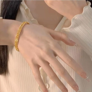Gros plan d'un bracelet triple couche plaqué or avec une texture argentée étincelante